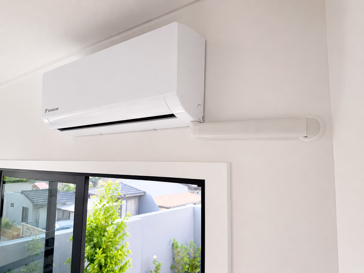 White refrigerant trunking running in a straight vertical line down an exterior wall to the outdoor unit