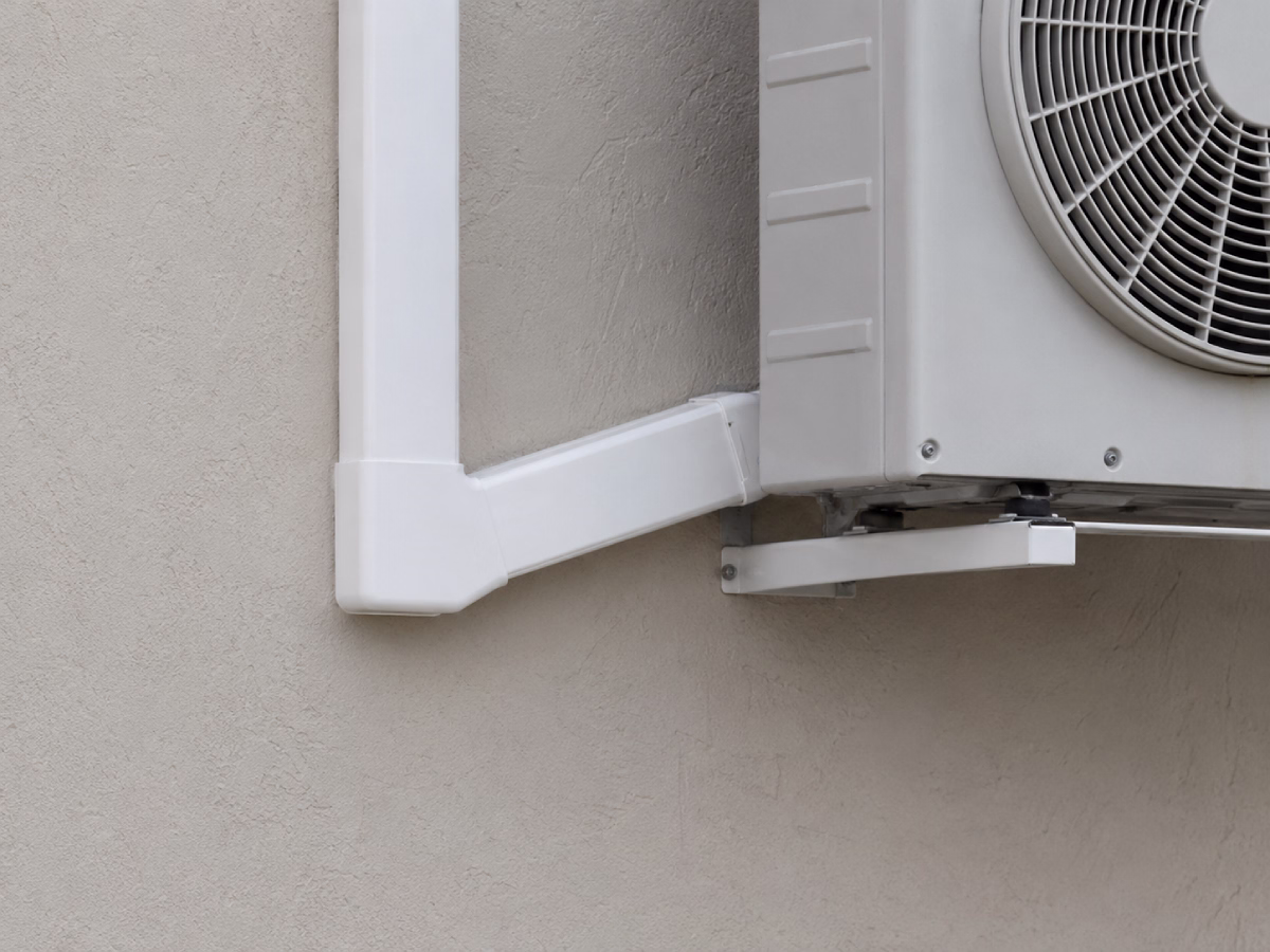 Neatly routed white trunking with clean elbow joints beside an outdoor unit